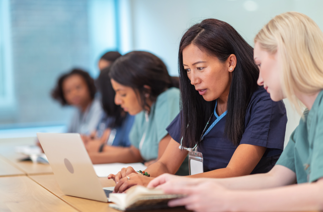 Nursing student reviewing notes and using a laptop to prepare for midterms